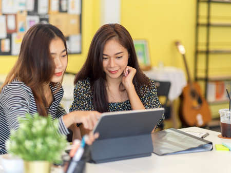 Two creative millennial women business startup owner talking and planning business model and...