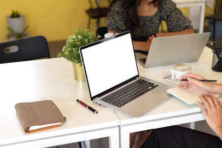 Cropped shot of work space in office, two female employee are working on laptop computer, blank...