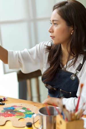 Portrait of beautiful artist drawing with passion, inspiration artwork, painting at art studioの写真素材