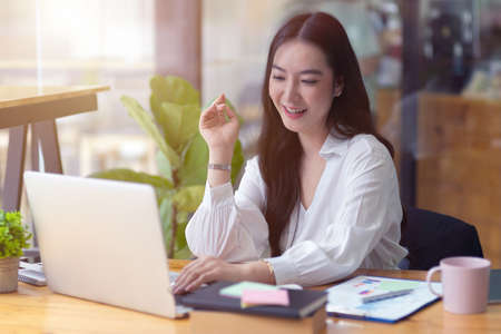 Young success business woman working in office, using laptop create creative works, making business plan, happy and pleased at workの写真素材