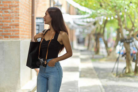 Attractive asian female traveller walking along the street, outdoor shopping mall, looking on the...