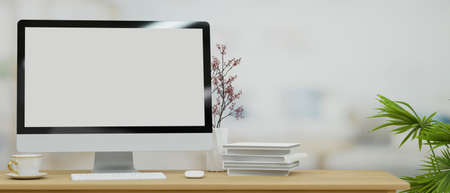 Workspace with desktop computer in blank screen mockup for your brands stand on wooden table with decor and space for display in blurred background, 3d rendering, 3d illustrationの写真素材