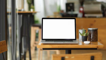 Laptop blank screen mockup stand on wooden table in coffee shop, blurred modern coffee shop in backgroundの写真素材