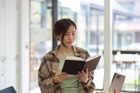 Hipster female architecture looking constructor plan on notebook at office, reading bookの写真素材