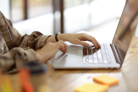 Cropped image of Attractive female freelancer working on laptop computer, young hipster college student typing on laptop keyboard on working deskの写真素材