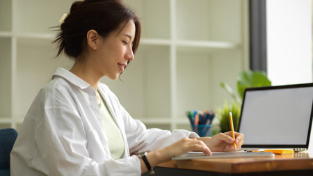 Young female architects or interior designers working in the office, taking notes, using laptop, planning project, laptop blank screen mockupの写真素材