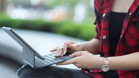 Cropped image of beautiful female freelancer using portable tablet and stylus pen working outside at parkの写真素材