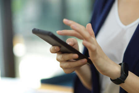 Cropped image, closeup of young success businesswoman use modern smartphone text or message with client partner online. business contactの写真素材
