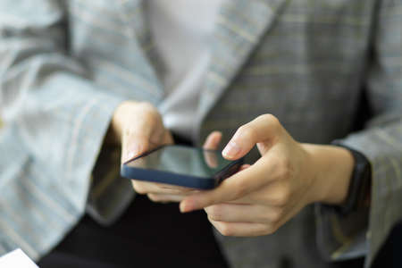 Businesswoman use smartphone for remote work, business contact. women's hands use a mobile phone for online shopping, social networking. Close up image.の写真素材