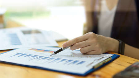 Company female auditor working in office, looking and checking business financial charts papers. Female business owner analysing business profit from financial reportの写真素材
