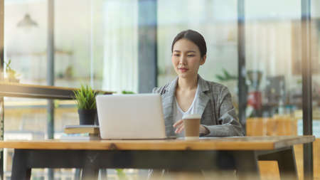 Success businesswoman working on laptop computer at cafe in lunch break, managing business projectの写真素材