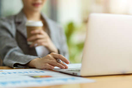 Cropped image of business woman checking her employee works while drinking coffee in cafe, female entrepreneur working on laptop at cafeの写真素材