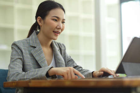 Cropped image of professional businesswoman working at her office via tablet, typing on keyboard, sending email to colleaguesの写真素材