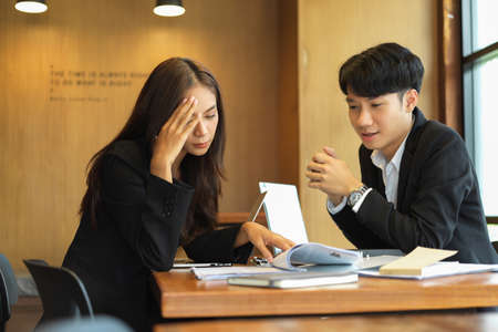 Business colleagues working together in boardroom. Pensive businesswomen explaining task to her co-workerの写真素材