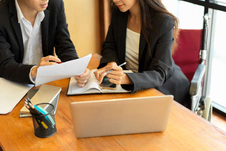 Two businesspeople discussing and working together, businesswoman is a disabled person in wheelchairの写真素材
