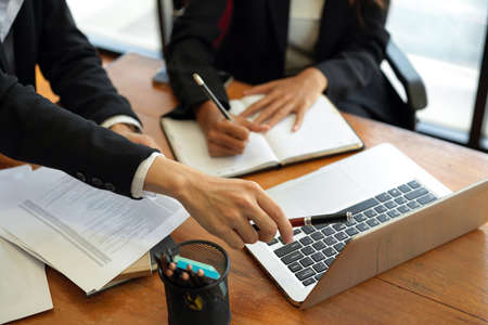 Cropped shot, Colleagues discussing work process. sitting at table with notebooks and laptop. Business partners brainstorming ideas at meetingの写真素材