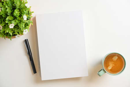 White blank book cover mockup with pen, coffee cup, plant on white background. Top viewの写真素材