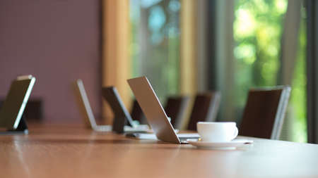 Laptop computer stand on wooden meeting table in modern board roomの写真素材