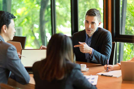 Diverse office concept, A caucasian male boss briefing and commenting on the business strategy process to his employees in a meeting.の写真素材