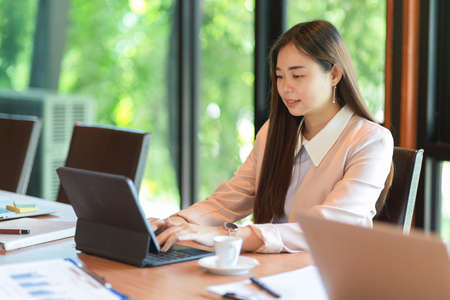 Businesswomen working on tablet computer and having meeting in boardroomの写真素材