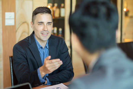 Business male executive having conversation and interviewing new employee in board roomの写真素材