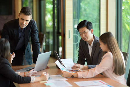 Business people discussing business project in conference room, Caucasian boss with asian employeesの写真素材