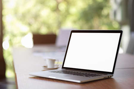 Opened laptop computer blank screen mockup for montage your brands on wooden desk and blurred backgroundの写真素材