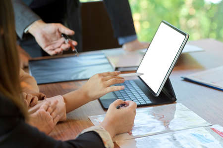Close-up and cropped image of a business team working and sharing business ideas while looking at a tablet screen, mockup of a tablet screenの写真素材