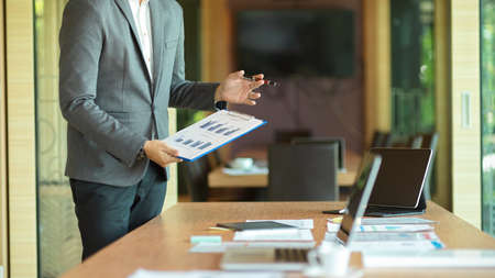 Cropped image of Success businessman standing and presenting his project to board members in meeting roomの写真素材
