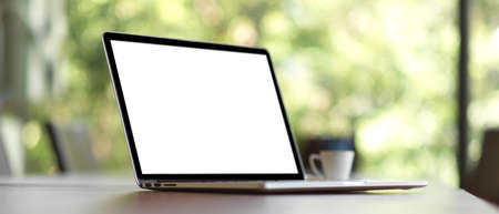 Closeup, Laptop computer white screen mockup for montage your web mockup on wooden desk over blurred greenery view in the backgroundの写真素材
