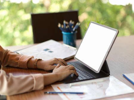 Success executive female typing working on portable tablet keyboard in office, tablet blank screen mockupの写真素材
