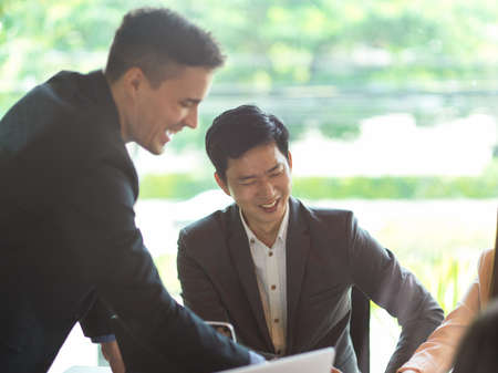 Diverse meeting with caucasian boss and asian employees. Happy and cheerful office meeting, teamwork conceptの写真素材