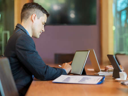 Successful businessman works on digital tablet while the meeting with business coworker in conference roomの写真素材