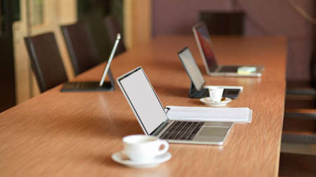 Opened laptop computer stand on wooden conference table in modern meeting roomの写真素材