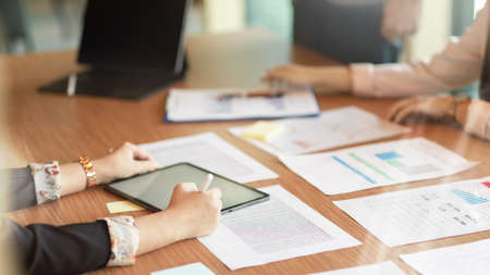 Cropped image of finance manager explain financial process to her assistant with digital tablet and financial report on conference tableの写真素材