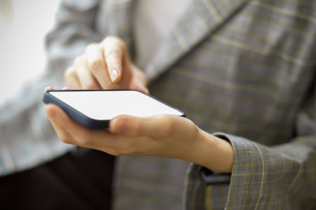 Close-up smart mobile phone in female hands with mockup screen for montage your bannerの写真素材