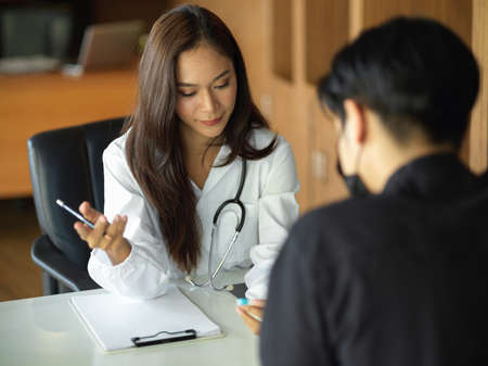 In a medical clinic, a female doctor consults and explains disease symptoms to a young patient.の写真素材