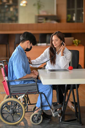 Young asian doctor hold stethoscope to checkup disabled patient heart rate examination in health centreの写真素材