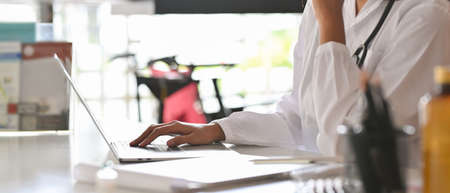 Cropped closeup image of a doctor or physician on a laptop computer reading a particular symptoms...
