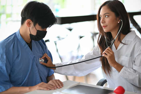 Female doctor checking patient body by stethoscope, checking heart rate, heartbeat or pulse at the clinicの写真素材