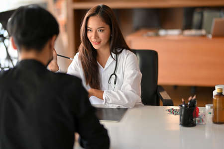 An Asian female doctor gives a patient advice and medication instructions. medical consulting, patient diagnosisの写真素材