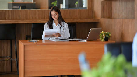 Female doctor, pharmacist or therapist working at her desk at hospital, writing medicine prescriptionsの写真素材