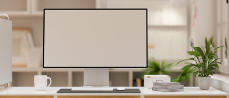 Close-up of Modern desktop computer in white screen mockup on working desk with cup, books and plant over blurred modern office interior. 3d rendering, 3d illustrationの写真素材