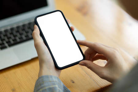 Close-up Female using smart mobile phone for message and browse internet blurred workspace in background. Cellphone blank screen mockupの写真素材
