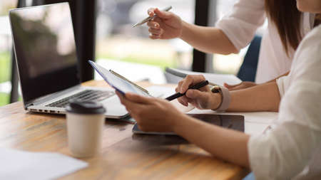 Close-up Senior businesswoman training her new young employee to analyse business charts on report in office. Corporationの写真素材