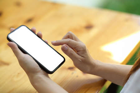 Close up Smartphone blank screen mockup for montage hold by young female, blurred backgroundの写真素材