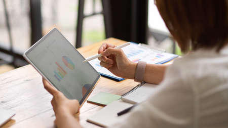 Close-up Senior female business entrepreneur analyses her business model on digital tablet. Business chart and graph on screenの写真素材
