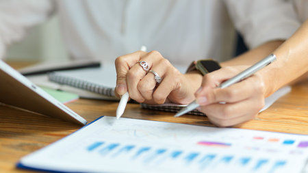 Cropped and close-up shot of female hands, Senior business female explains business charts to her...