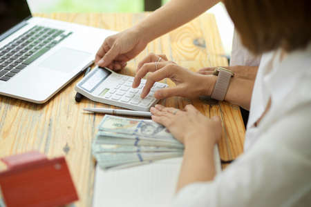 Business female entrepreneur calculating money on calculator to pay business expenses. payment, counting, depositの写真素材