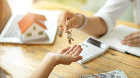 Close-up of a female real estate agent handing over the keys to the new owner of a house. Purchasing a homeの写真素材